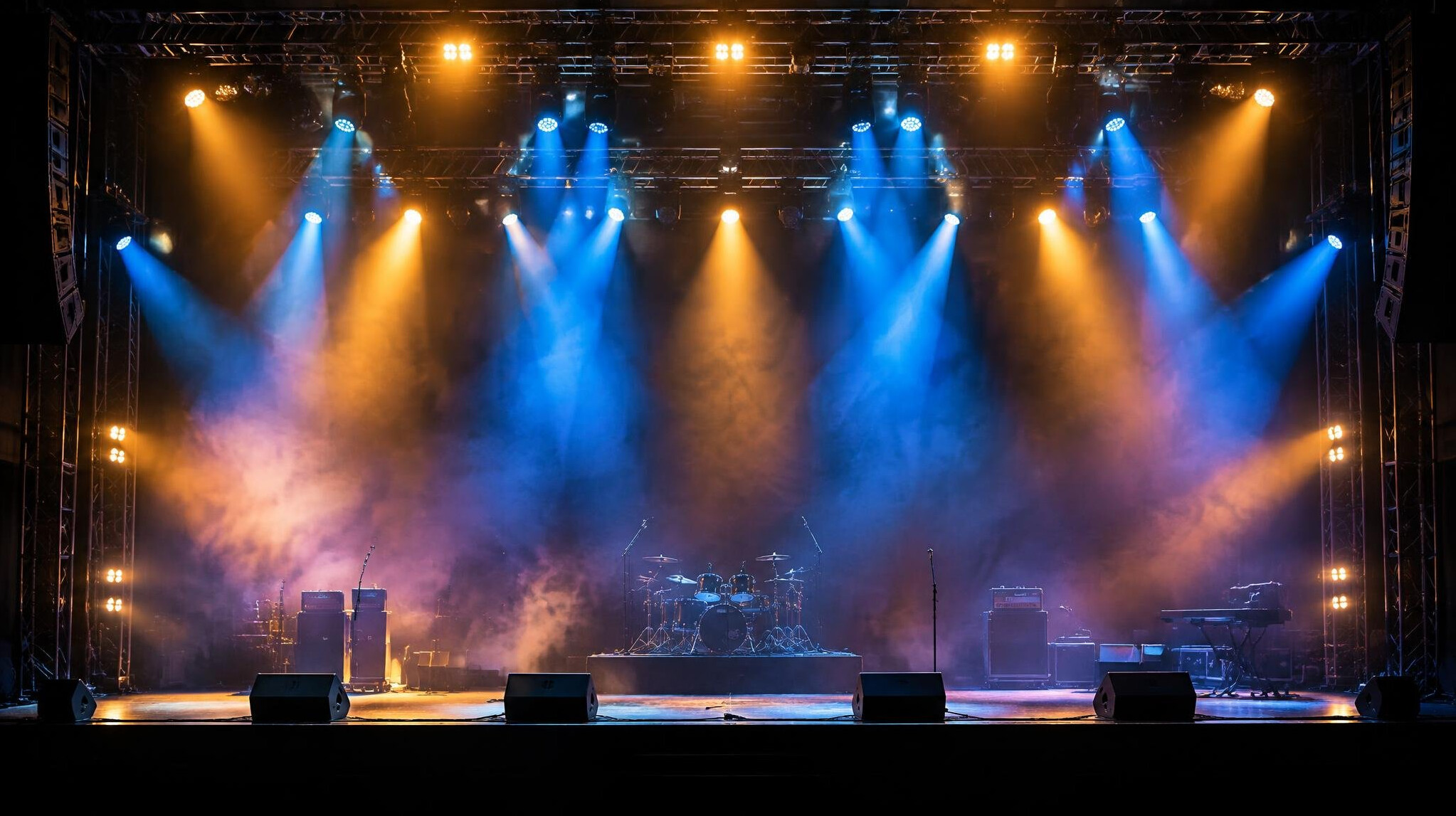 Stage lighting rig glowing above an empty concert stage
