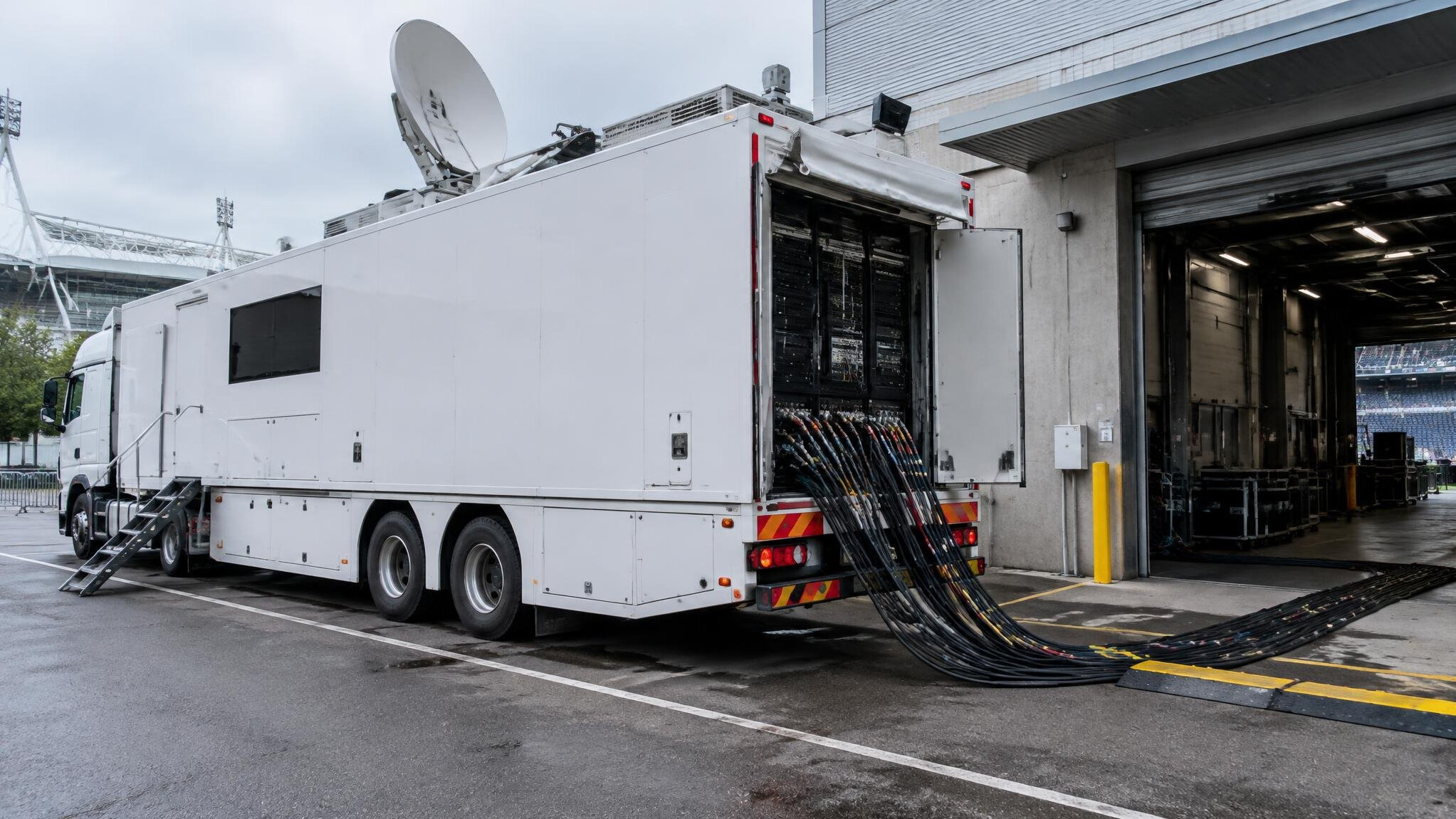 Outside broadcast truck parked near a venue with cables
